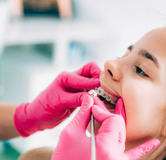Orthodontist checking girl’s dental braces